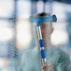 Clean and hygienic. Shot of a young man cleaning the windows in the office