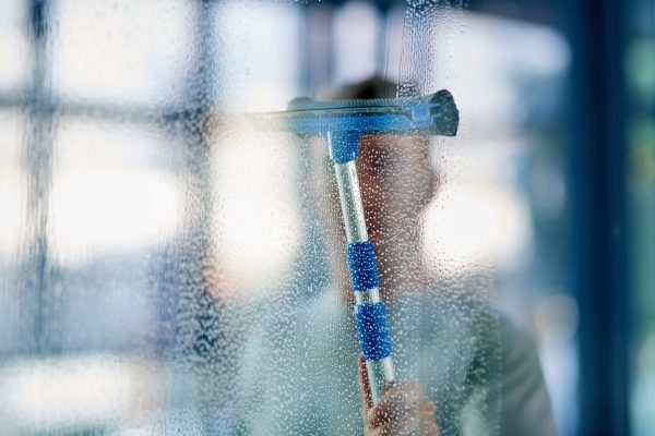 Clean and hygienic. Shot of a young man cleaning the windows in the office