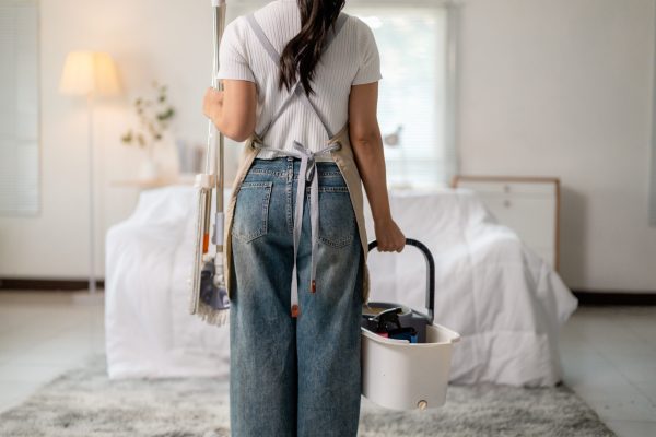 Housekeeping professional carrying cleaning supplies, moving through hallway for thorough room sanitizing