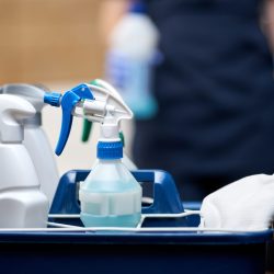 Close up of basket of cleaning tools for hotel room cleaning. Housekeeping and hygiene concept